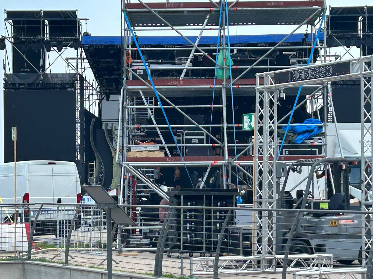 Allestimento di maxi schermo in piazza pubblica con pubblico seduto, palco illuminato, corso cittadino con divieti di sosta