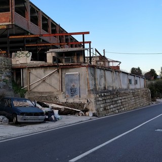 La discarica abusiva e il cartello sull'auto abbandonata