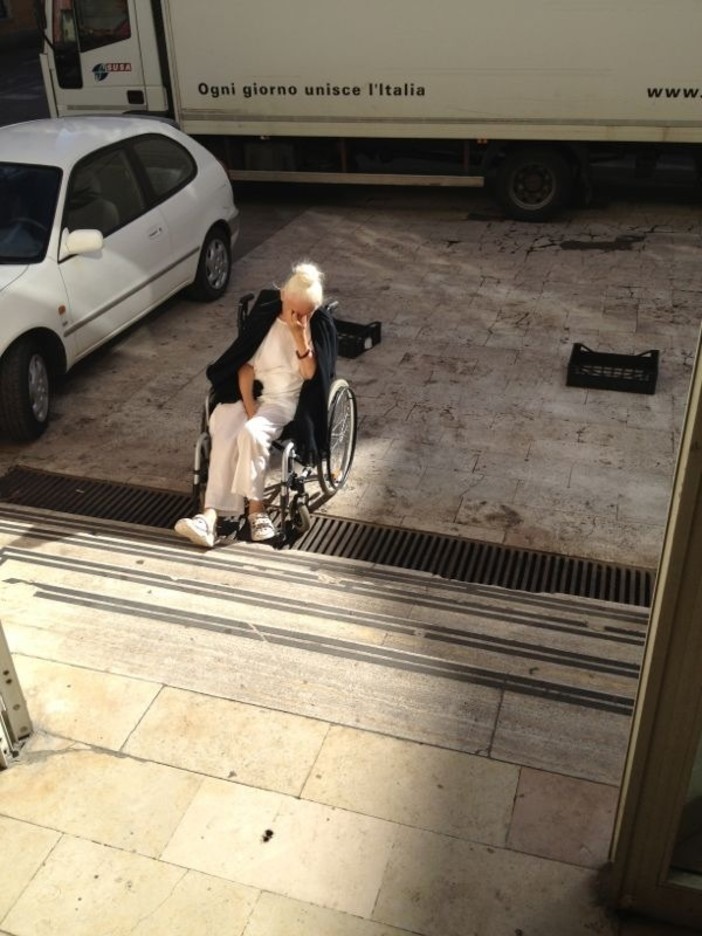 Un'anziana donna sulla sedia a rotelle impossibilitata ad accedere al mercato Un'anziana donna sulla sedia a rotelle impossibilitata ad accedere al mercato