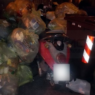Sanremo: parcheggia accanto ai bidoni della differenziata e ritrova lo scooter sommerso dai sacchetti (Foto)