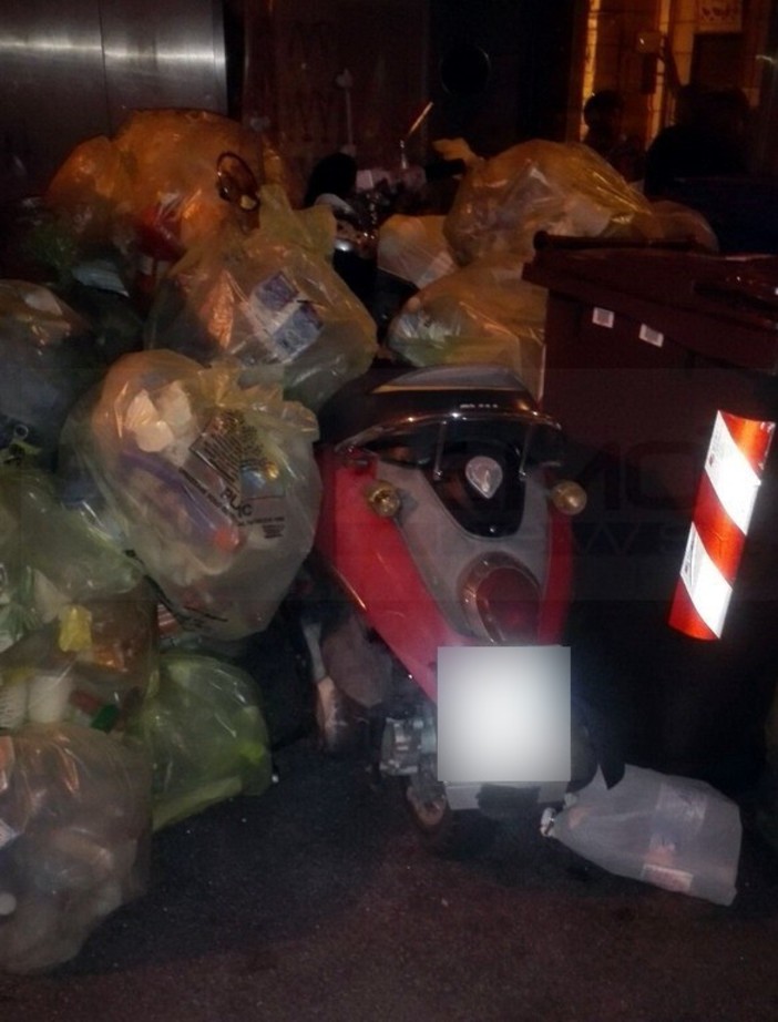 Sanremo: parcheggia accanto ai bidoni della differenziata e ritrova lo scooter sommerso dai sacchetti (Foto)