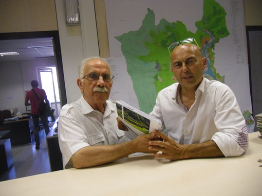 La foto mostra il geometra Colecchia mentre consegna al geometra Fassola copia del progetto. La foto mostra il geometra Colecchia mentre consegna al geometra Fassola copia del progetto.