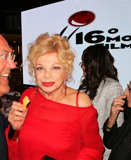 Sandra Milo mentre degusta una bugia di Vallebona con acqua di fior di arancio